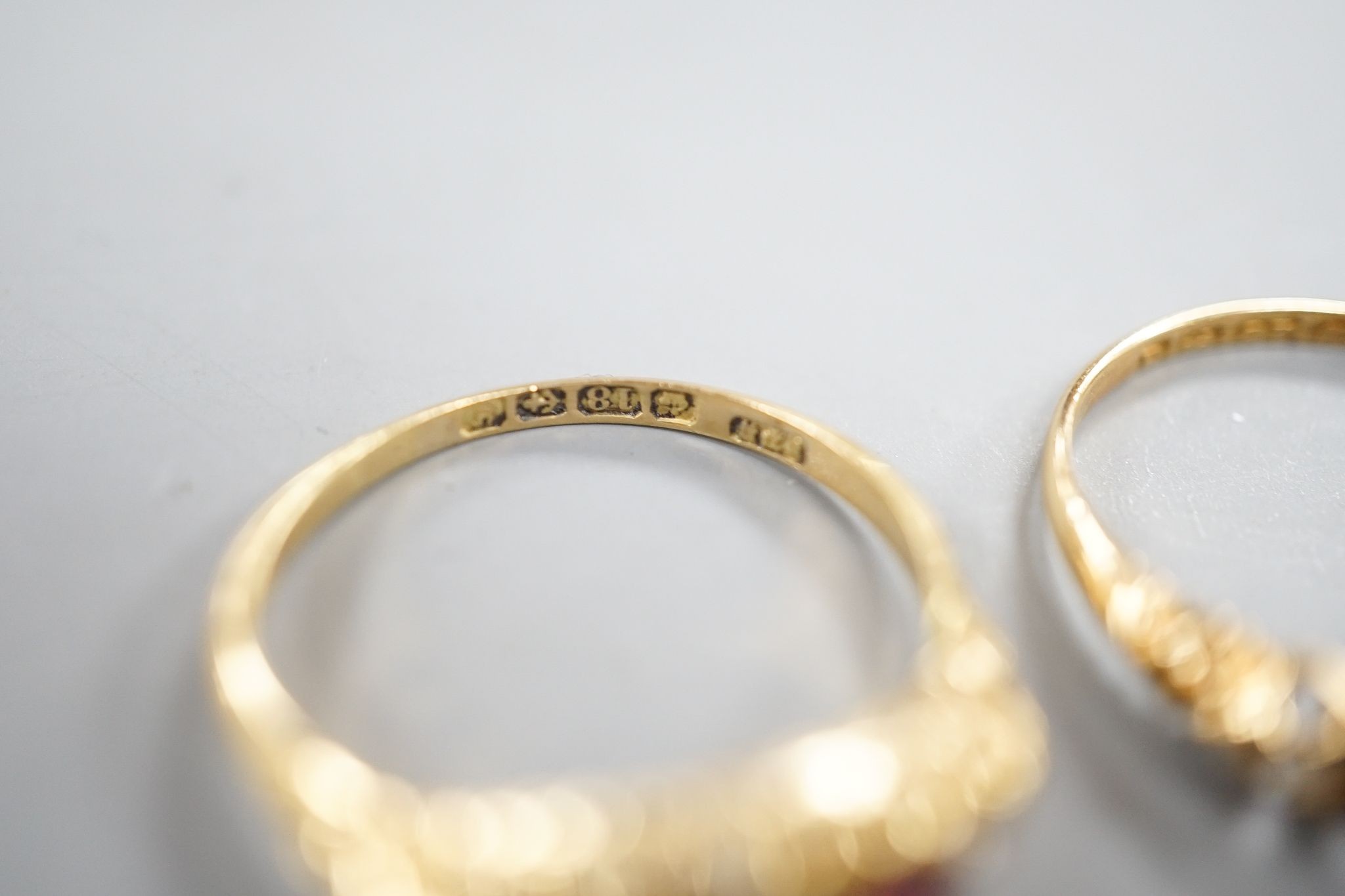 Two early 20th century 18ct gold, ruby and diamond five stone set half hoop rings, sizes m and P/Q, gross weight 5.1 grams.